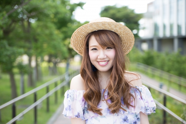 麦わら帽子をかぶった笑顔の年下女性